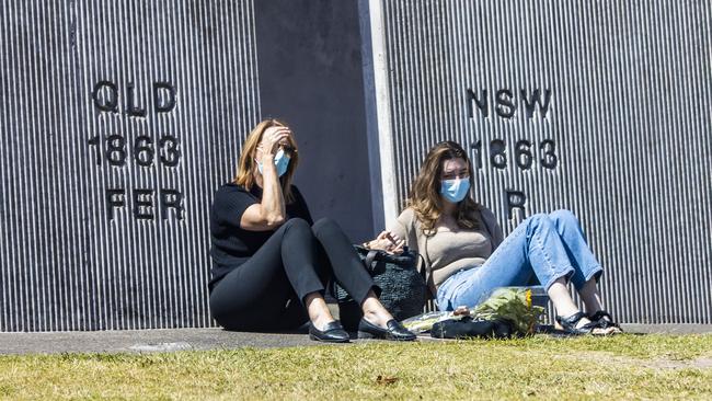 An emotional scene at the Queensland and NSW border at Coolangatta where two people hold hands that are separated by the border restrictions. Picture: NIGEL HALLETT