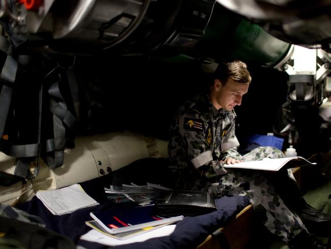 Seaman in training Callum Donald studies his part three submarine sea qualification taskbook inside the weapons stowage compartment of one of the Navy’s existing submarines. Picture: Royal Australian Navy