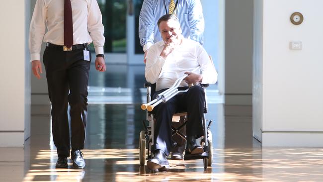 Jamie Briggs arrives in a wheelchair at a party room meeting at Parliament House in Canberra.