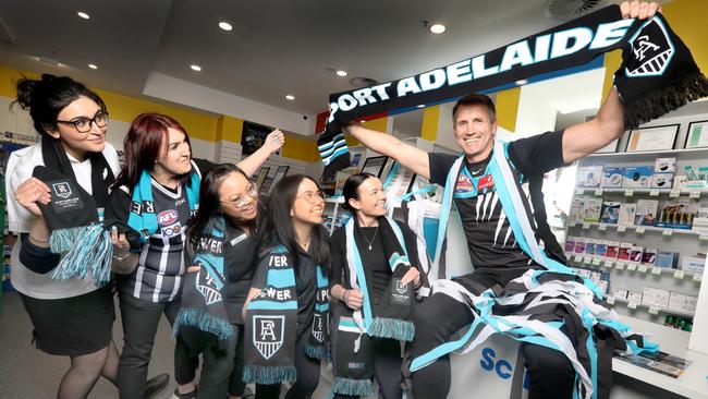 Darryl Wakelin in his 2004 premiership guernsey with staff at his pharmacy in Arndale, that is already decked out with Port memorabilia in readiness for finals. Picture Dean Martin