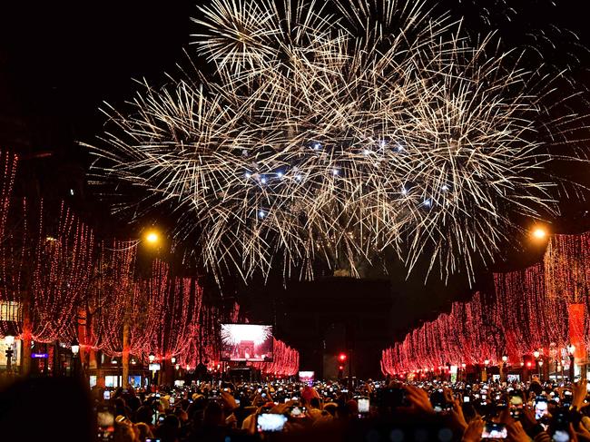 People take pictures of the fireworks erupting in the sky over the Arc de Triomphe during the New Year's celebrations on the Champs Elysees avenue, in Paris. Picture: AFP