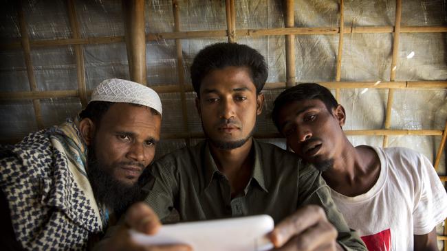 Refugee Mohammad Karim, 26, center, shows a mobile video of the massacre to other refugees in Kutupalong refugee camp, Bangladesh.(AP Photo/Manish Swarup)