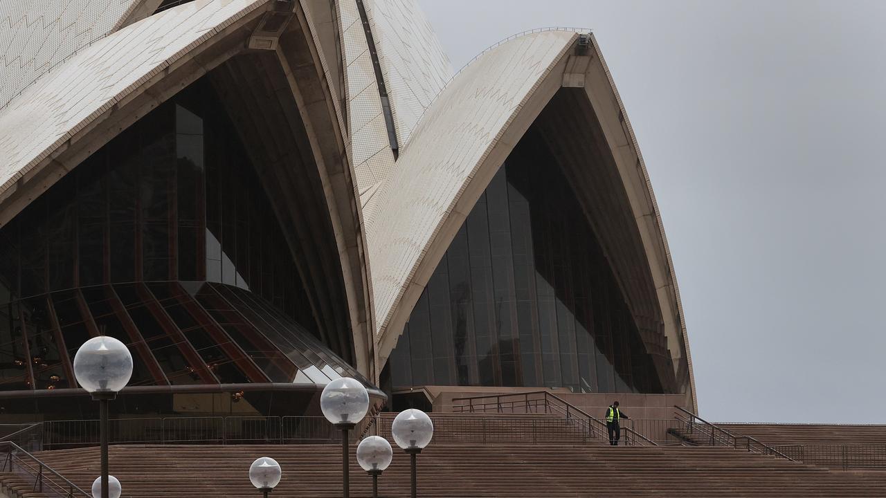 A guard watches over a deserted Sydney Opera House in Circular Quay as storms were brewing along the coast. Picture: NCA NewsWire/Dylan Coker