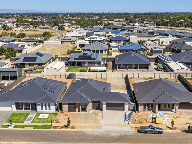 Aerial view, new rural housing development being built on former quality food-producing farmland. Railway line for freight transport and tourist trains can be seen in the background with potential for commuter trains. Close view of houses