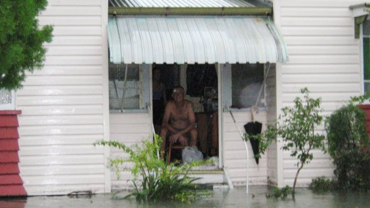 A resident sits on their porch as their front yard becomes a creek during the 2008 natural disaster in Mackay. Picture: Daily Mercury Archives