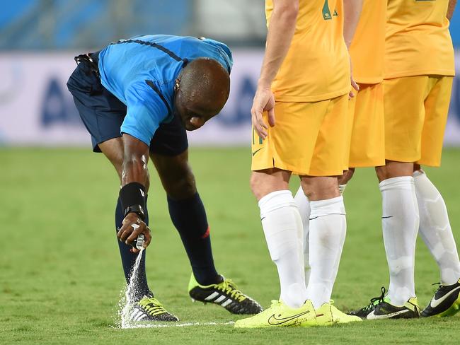 Ivorian referee Noumandiez Doue sprays a free kick marker on the pitch during a Group B football match between Chile and Australia.