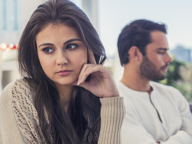 Couple fighting at home. Man and woman are both looking angry and sad, sitting on a sofa in a luxury home. Young couple