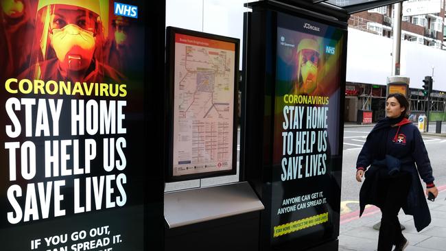 A pedestrian walks past signage about coronavirus in central London. Picture: AFP