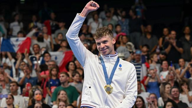 Gold medallist  France's Leon Marchand celebrates on the podium of the men's 200m breaststroke swimming event during the Paris 2024 Olympic Games at the Paris La Defense Arena in Nanterre, west of Paris, on July 31, 2024. (Photo by Jonathan NACKSTRAND / AFP)