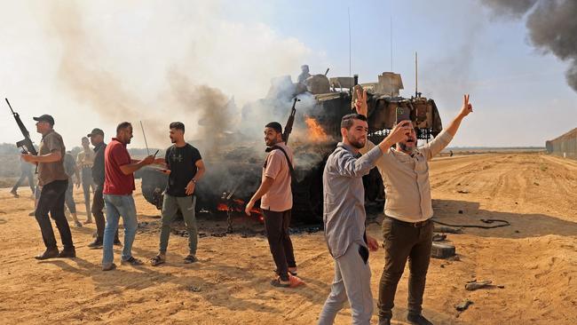 Palestinians take control of an Israeli tank after crossing the border fence with Israel from Khan Yunis in the southern Gaza Strip on October 7.