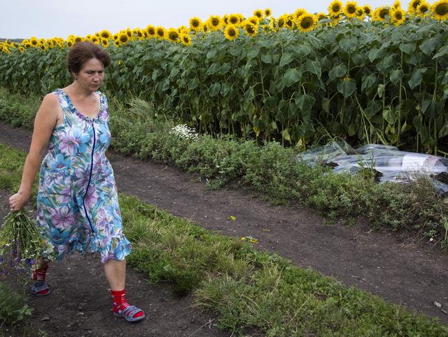 A woman walks past a body covered with a plastic sheet near the crash site. Picture: Dmitry Lovetsky