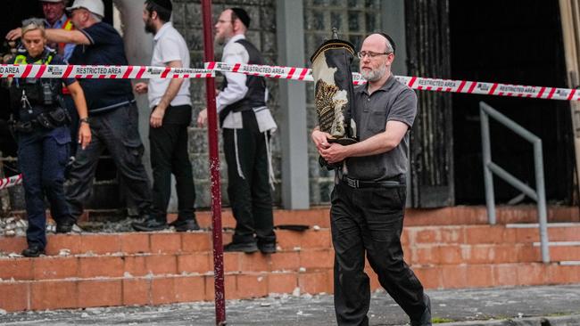 A member of the Jewish community recovers an item from the Adass Israel Synagogue in Melbourne, following an arson attack. Picture: Getty