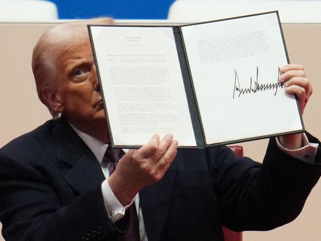 WASHINGTON, DC - JANUARY 20: U.S. President Donald Trump holds up an executive orders after signing it during an indoor inauguration parade at Capital One Arena on January 20, 2025 in Washington, DC. Donald Trump takes office for his second term as the 47th president of the United States.   Christopher Furlong/Getty Images/AFP (Photo by Christopher Furlong / GETTY IMAGES NORTH AMERICA / Getty Images via AFP)