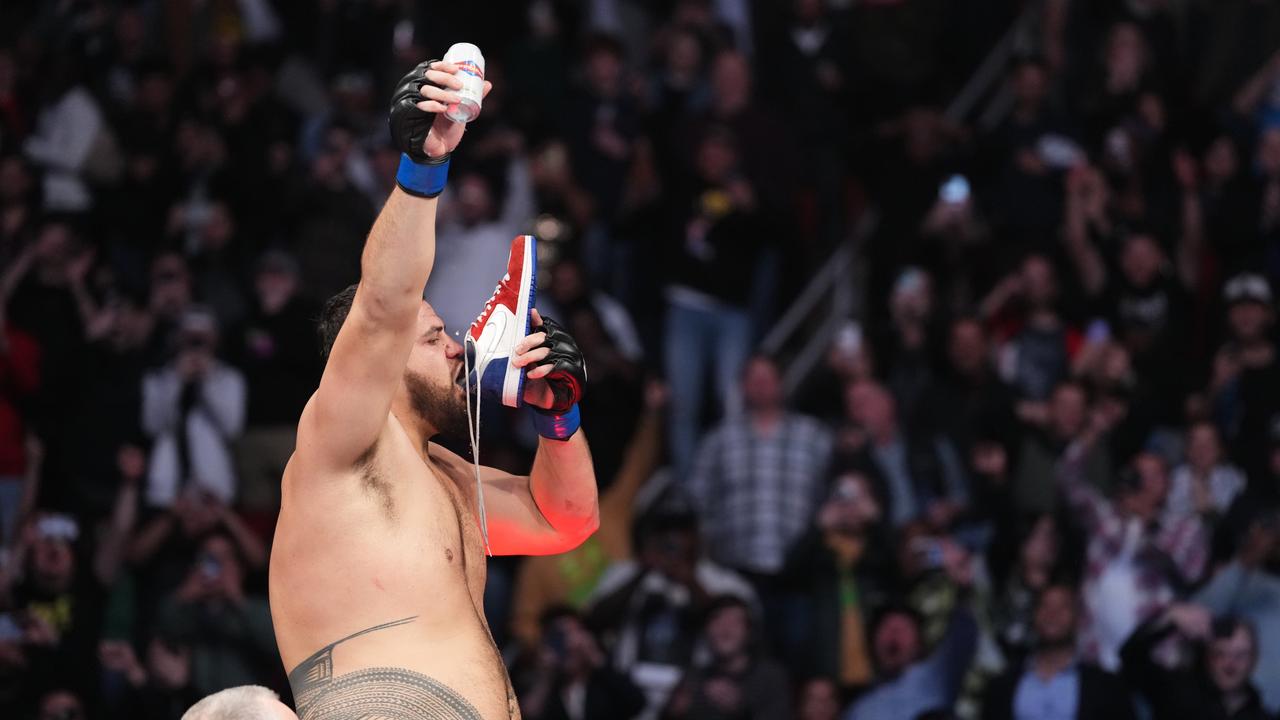 Tai Tuivasa of Australia celebrates with the fans by performing a shoey after defeating Derrick Lewis in their heavyweight fight during the UFC 271