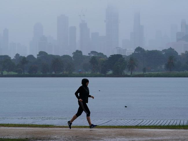 A person jogs in isolation as heavy rain begins to fall in Melbourne, Wednesday, April 29, 2020. Victoria's harsher social distancing laws maintain a ban on all but the most basic outdoor activities. (AAP Image/Michael Dodge) NO ARCHIVING