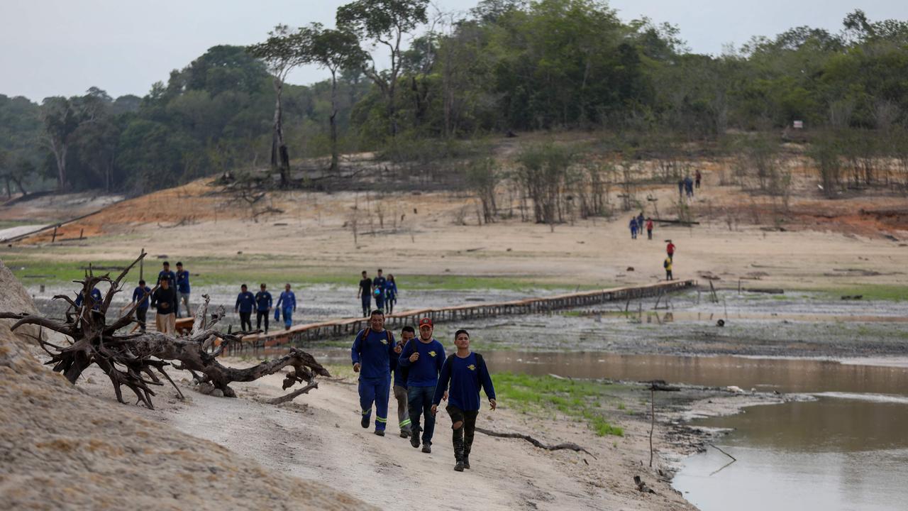 Employees of a shipyard walk over a makeshift bridge to cross the Taruma-Acu river, a tributary of the Rio Negro river, which is at a very low level due to the severe drought in Manaus, Amazonas, northern Brazil. Picture: Michael Dantas / AFP