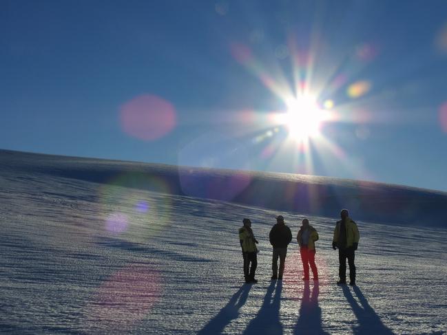 Expeditioners during an evening walk as the sun dips low on the horizon at Cape Denison in Antarctica. Picture: David Killick