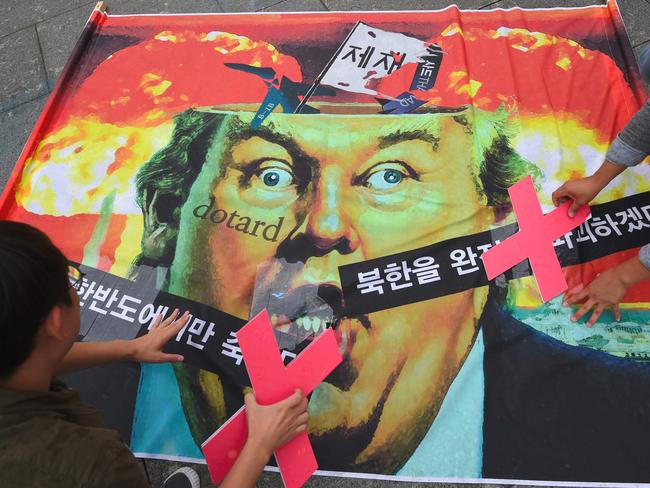 Anti-war activists attach "X" signs on a banner showing a caricature of US President Donald Trump during an anti-Trump rally near the US embassy in Seoul. Picture: AFP / JUNG Yeon-Je