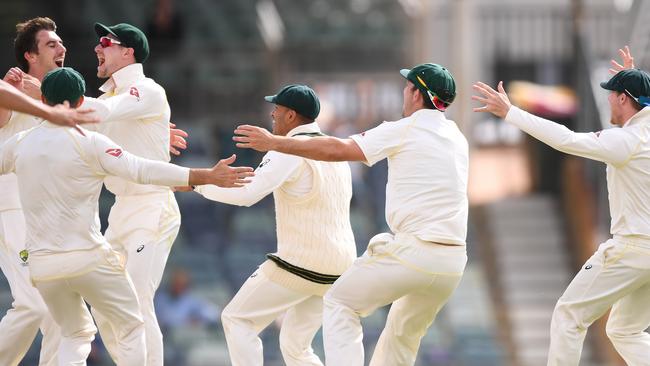 Australia players celebrate with Pat Cummins (left) after he took the wicket that wrapped up the third Test in Perth on Monday.