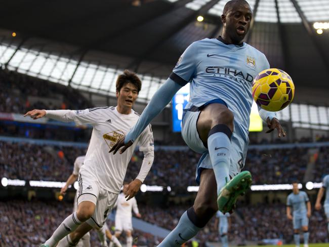 Manchester City's Yaya Toure, centre, keeps the ball from Swansea's Ki Sung-Yeung, left, during the English Premier League soccer match between Manchester City and Swansea at the Etihad Stadium, Manchester, England, Saturday Nov. 22, 2014. (AP Photo/Jon Super)