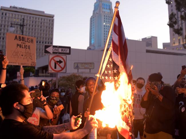 A man burns an upside down US flag at a protest in LA. Picture: AFP