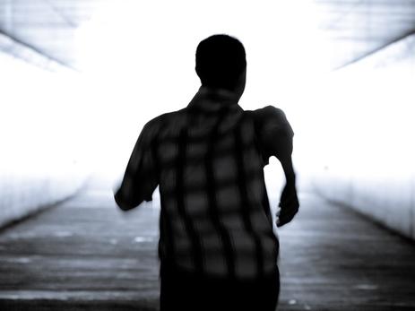 Black and white conceptual image.Man is running out of the tunnel into the light.  Motion blur. He is determined to get out of darkness into the light. There is hope and determination.