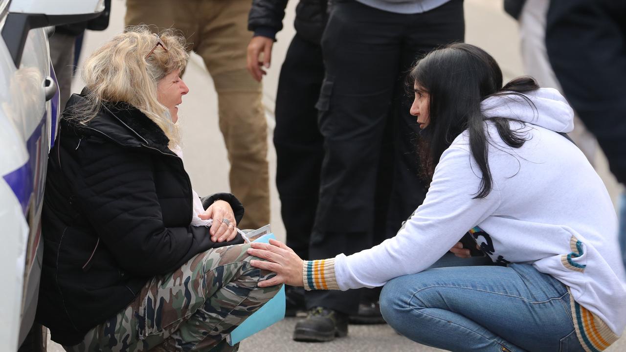 A woman kneels by a police car as she cries in the street. Picture: Valery Hache/AFP