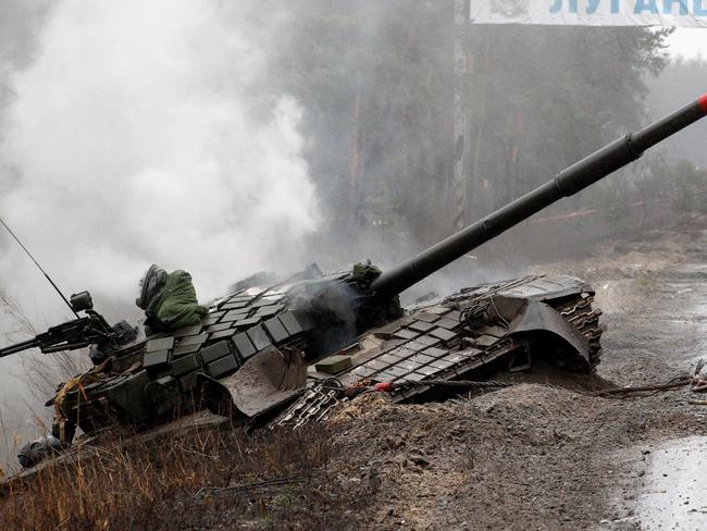 Smoke rises from a Russian tank destroyed by the Ukrainian forces on the side of a road in Lugansk region on February 26, 2022. - Russia on February 26 ordered its troops to advance in Ukraine "from all directions" as the Ukrainian capital Kyiv imposed a blanket curfew and officials reported 198 civilian deaths. (Photo by Anatolii Stepanov / AFP)