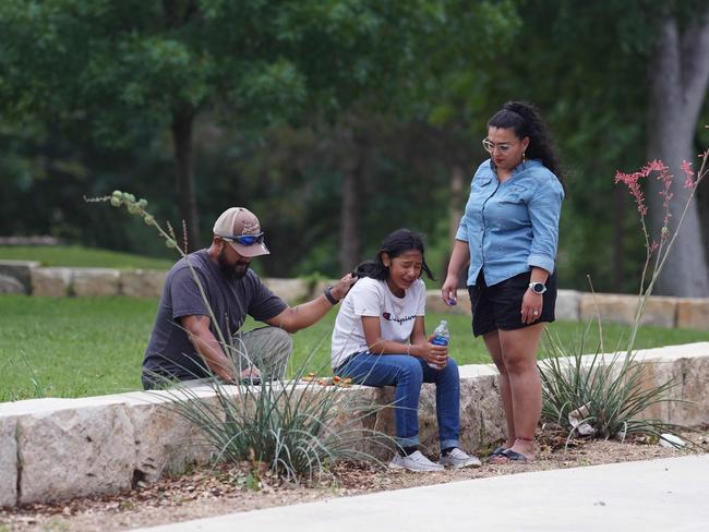 A girl cries, comforted by two adults, outside the Willie de Leon Civic Center where grief counselling will be offered in Uvalde, Texas, on May 24, 2022.