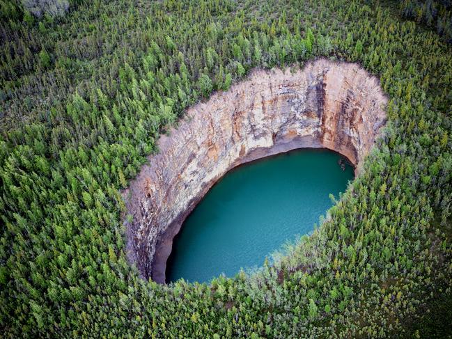4/12BEAR ROCK SINKHOLE, NORTHWEST TERRITORIES
If you ever find yourself in the dense forests between Tulita and Norman Wells, be careful where you step. There are dozens of sinkholes in the Sahtu Region, but none are quite as impressive as the Bear Rock Sinkhole – with its plunging sides and deep aquamarine waters. According to scientists, the sinkhole was formed when a subterranean cave collapsed, but for the Indigenous Dene people, Bear Rock is a highly sacred sight. According to legend, a mythological figure known as Yamoria killed giant beavers who were terrorising the people, hanging their skins on the rock.