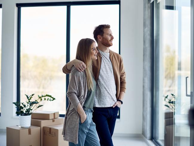 Young happy couple enjoying the view through the window in their new home