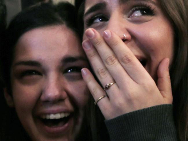 Supporters of left-wing Syriza party react as they watch the exit poll results at an election kiosk in Athens, Sunday, Jan. 25, 2015. A Greek state TV exit poll was projecting that anti-bailout party Syriza had won Sunday’s parliamentary elections _ in a historic first for a radical left wing party in Greece. (AP Photo/Lefteris Pitarakis)