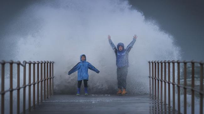 Maeva and her son Rennie drenched by waves on a pier at Middle Park. Picture: David Caird