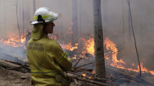 A firefighter watches a controlled fire amid work to build a containment line at a wildfire near Bodalla, in NSW, on January 12. Picture: AFP