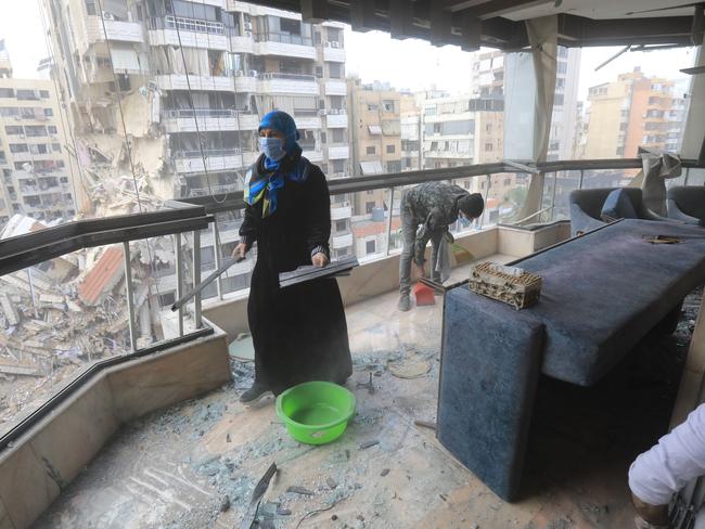 People clear debris and rubble from their apartment after returning home following the ceasefire. Picture: AFP