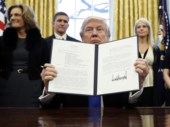 Ms Conway stands (right) behind Donald Trump in the Oval Office as he holds up the seven country Muslim entry ban after signing the executive order. Picture: AP/Alex Brandon.