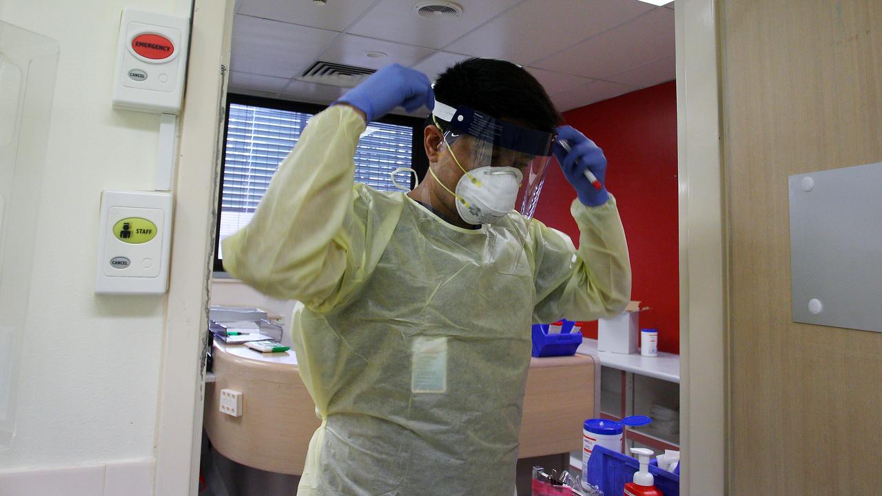 Nurse Laxman Adhikari fits a face shield prior to conducting a nasal swab test in the clinical assessment room at St George Hospital in Sydney. Picture: Lisa Maree Williams/Getty Images