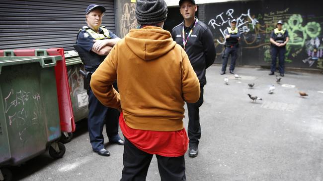 A police officer and council compliance manager speak to a man near Bourke St. Picture: David Caird