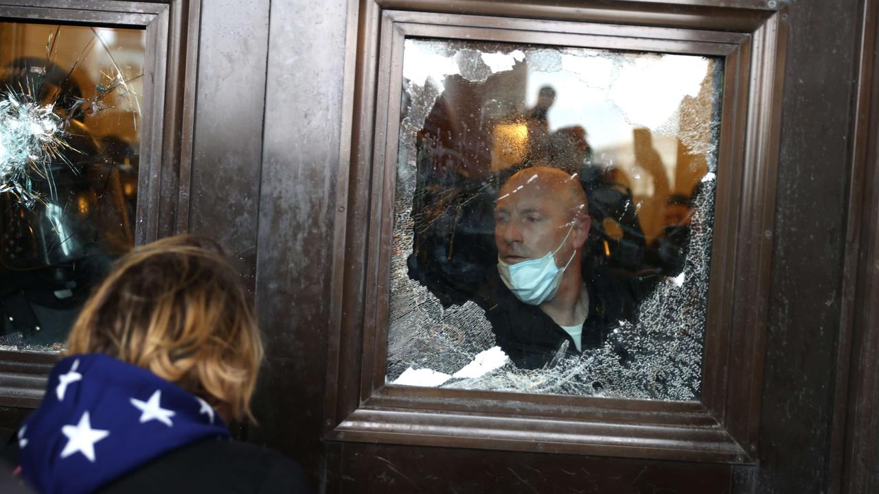 A police officer looks out of a broken window as protesters gather on the US Capitol Building. Picture: Tasos Katopodis/Getty Images/AFP