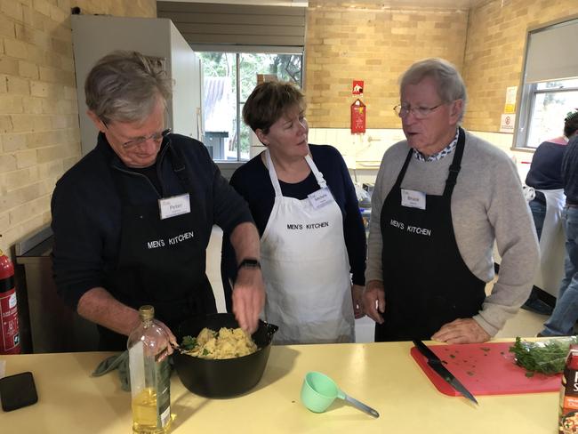 Peter Osborne (left), volunteer instructor Michelle Jansen and Bruce Johnson finish off the Moroccan chicken dish during a Men's Kitchen Northern Beaches cooking skills session at the Forestville Community Hall. Picture: Jim O'Rourke