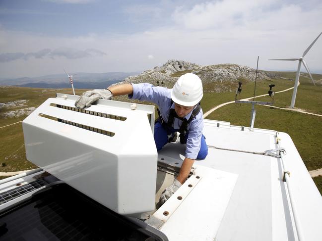 An employee wears a safety harness and hard hat as he checks the oil cooling system on the top of a wind turbine unit manufactured by Gamesa Corp. Tecnologica SA and operated by Enel Green Power SpA, the clean-energy unit of Italy's biggest utility Enel SpA at their wind farm in Frosolone, Italy, on Tuesday, July 29, 2014. Enel SpA, Italy's largest utility, will steer investments into Latin America and renewable energy as recession damps electricity demand in its biggest market. Photographer: Alessia Pierdomenico/Bloomberg