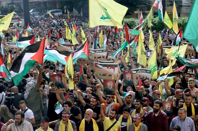 Hezbollah supporters wave the Palestinian flag alongside their movement's yellow emblem at a solidarity rally in Beirut