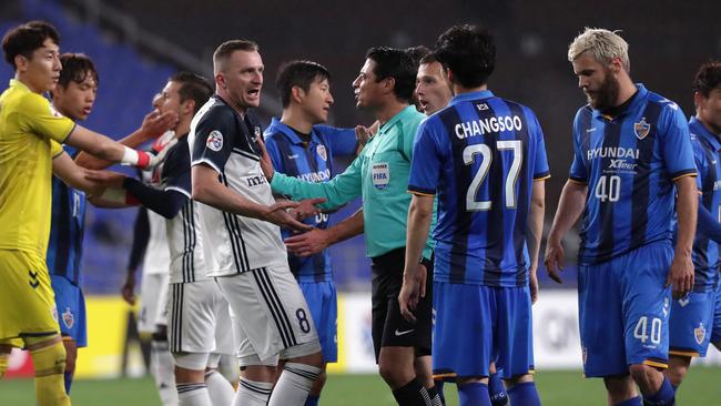 The referee talks to Melbourne Victory striker Besart Berisha as players remonstrate on Wednesday night.