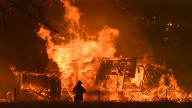 NSW Rural Fire Service crews fight the Gospers Mountain Fire as it impacts a structure at Bilpin. Police have arrested a man charged with obtaining $110,000 in grant funding. Picture: Dan Himbrechts