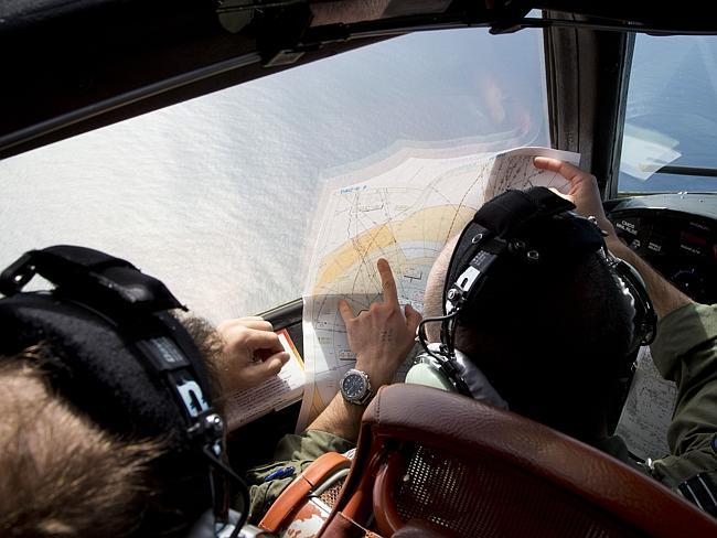 Search...Flight Lt. Jayson Nichols looks at a map onboard a RAAF search operation over the Indian Ocean. Picture: AP