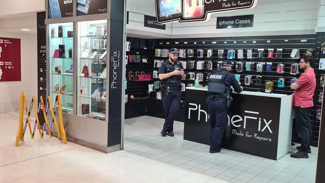 Police interview a shopkeeper in City Cross Arcade after security guard was stabbed.