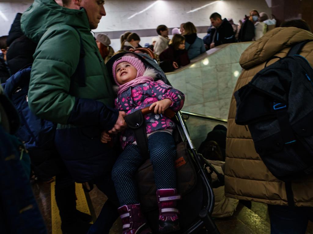 A child is carried down the steps in her stroller as hundreds of people seek shelter underground, on the platform, inside the dark train cars, and even in the emergency exits, in Kharkiv, Ukraine. Picture: Marcus Yam