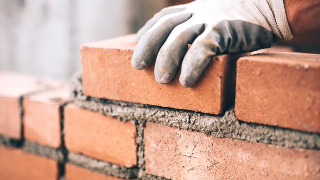 Close up of industrial bricklayer installing bricks on construction site