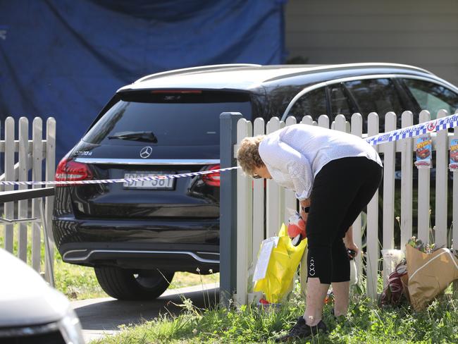 A mourner brings tributes to lay at a crime scene on Chapman Pde, Faulconbridge, where Police continue to investigate the deaths of brothers Russell and Ben Smith. Picture by Max Mason-Hubers