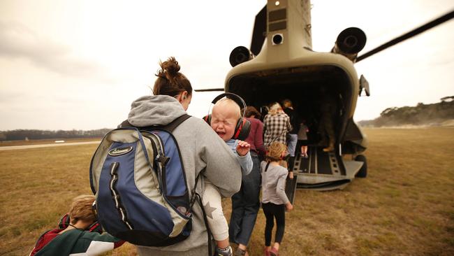 A mother and her children were among the last evacuees airlifted from Mallacoota airport on Sunday. Picture: David Caird